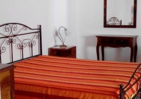 nella foto vediamo una camera da letto con un copriletto arancione di una casa in vendita a salve